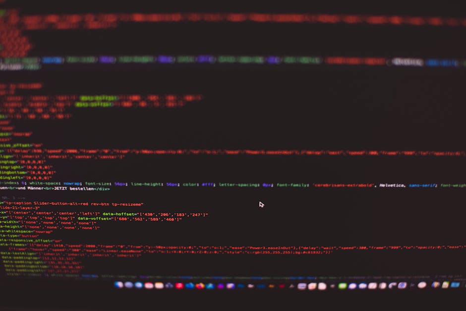 A person using a laptop on a dark surface, displaying a coding interface with multiple lines of code in various colors, including green, blue, and white. The hands are positioned on the keyboard, with